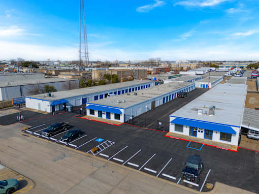 A parking lot with several cars and a large building with a blue roof.