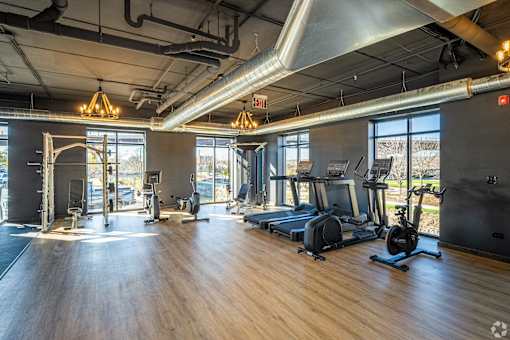 a gym with fitness equipment and windows in a building with wood floors