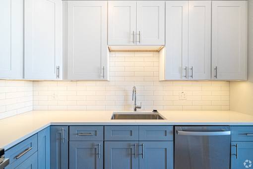a white and blue kitchen with blue cabinets and a sink