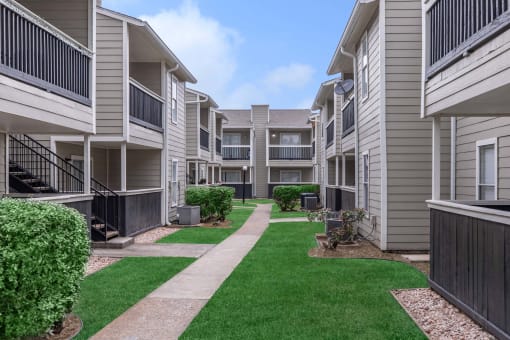 Building exterior walk path at Royal Wildewood Manor Apartments, Texas, 77531
