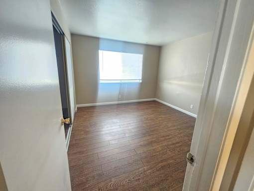 A room with wooden flooring and a window.