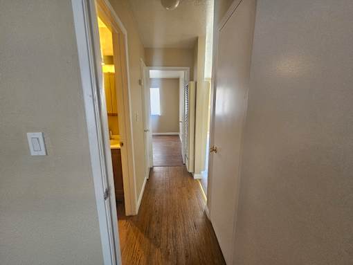 A long hallway with doors on both sides and a light switch on the wall.