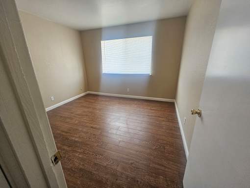 A room with wooden flooring and a window letting in light.