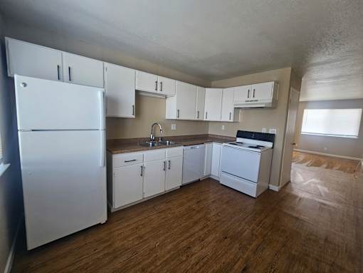 A kitchen with white appliances and cabinets.
