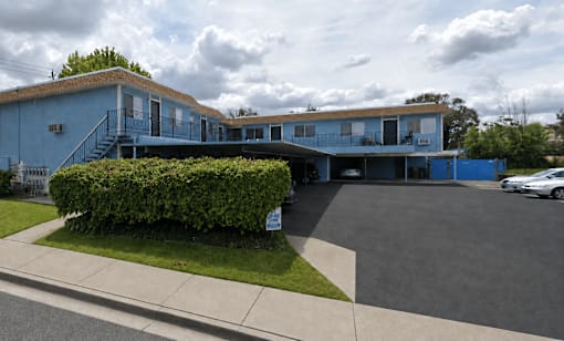 A blue building with a parking lot in front.