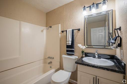 A bathroom with a toilet, sink, and mirror.