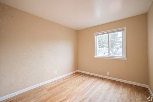 A room with a window and wooden flooring.