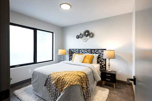 A bedroom with a bed, two lamps, and a wall hanging.