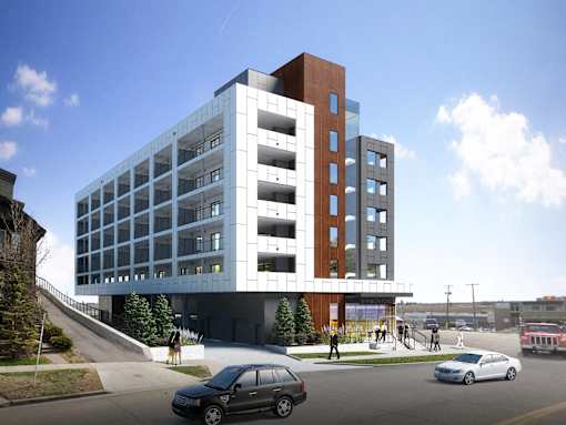 A modern multi-story building with a parking lot in front.