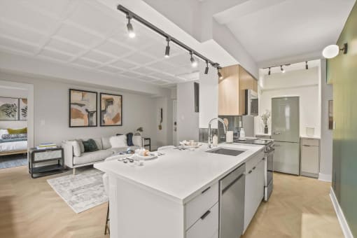 a white kitchen with an island and a living room
