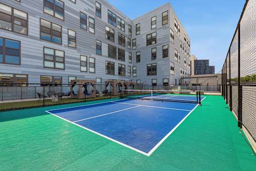 A tennis court is located between two buildings.