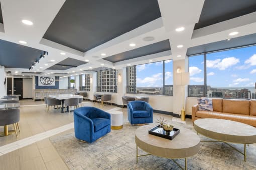 a lounge area with blue chairs and a view of the city