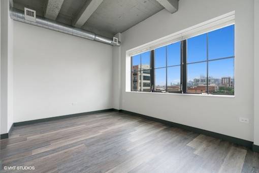 an empty living room with a large window and wood floors