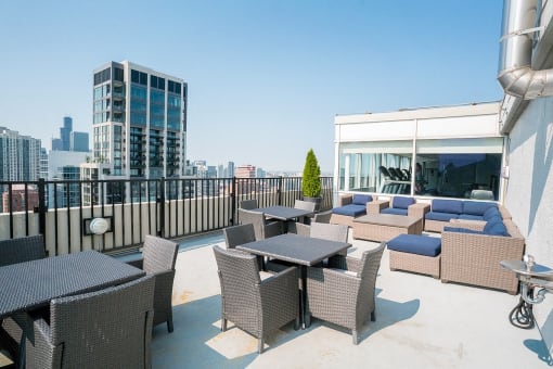 a rooftop patio with tables and chairs and a view of the city