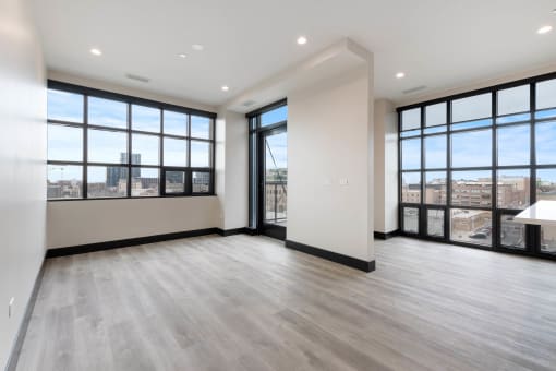 an empty living room with large windows and a city view