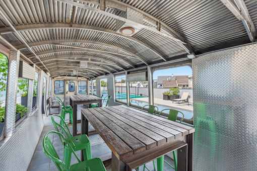 A long wooden table with green chairs is on the left side of the image.