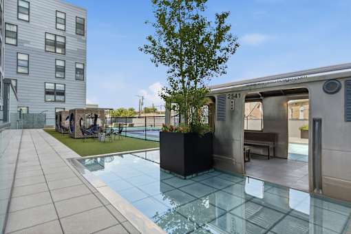 A modern building with a pool and a tree in a planter.