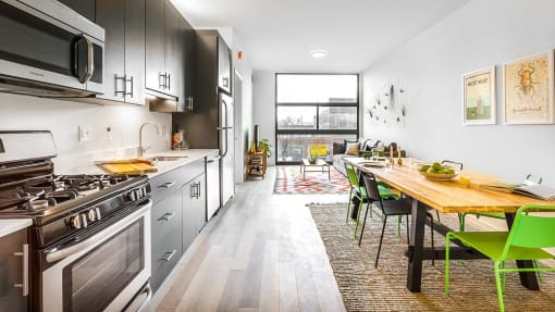 a kitchen with stainless steel appliances and a wooden table with green chairs