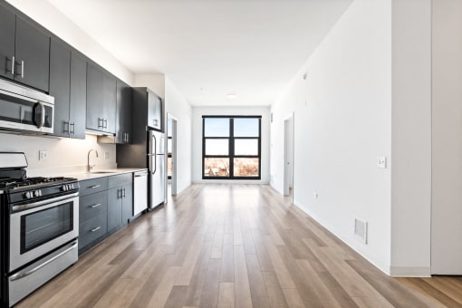 an empty kitchen with stainless steel appliances and wooden floors