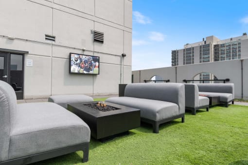 a lounge area with chairs and a fire pit on the roof of a building