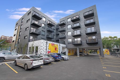 a grey apartment building with cars parked in front of it
