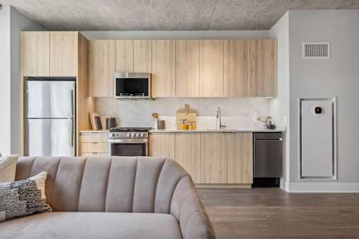 A modern kitchen with wooden cabinets and a grey sofa.
