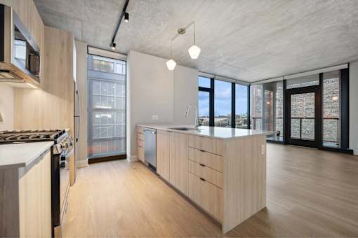 A modern kitchen with wooden cabinets and a large window.