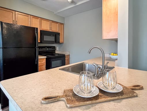 View from breakfast bar of well equipped kitchen with wood cabinetry and black appliances