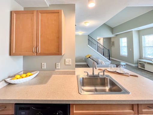 View from kitchen sink and breakfast bar towards living area of great room and stairs to second floor loft area