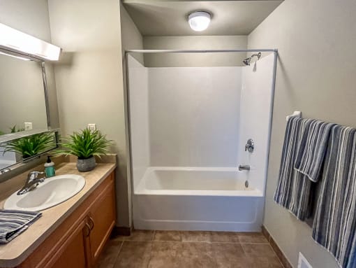 Full bathroom with shower/tub combo, wood cabinetry, and tile floor