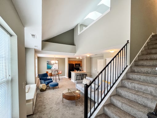View from 1st-floor bedroom past staircase to open-plan great room with living, dining, and kitchen areas