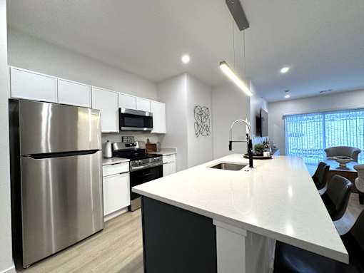 View of typical kitchen with stainless steel appliances and breakfast bar overlooking the great room