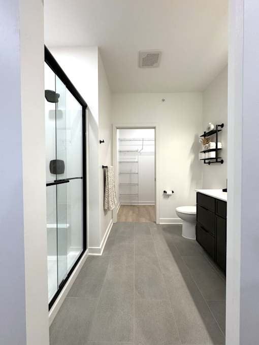 View of typical en-suite bathroom leading to walk-in closet from primary bedroom