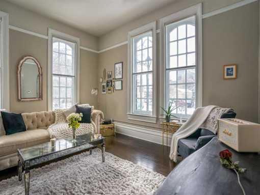 Great room living area with soaring ceilings, refurbished original hardwood floors, and nearly floor to ceiling windows
