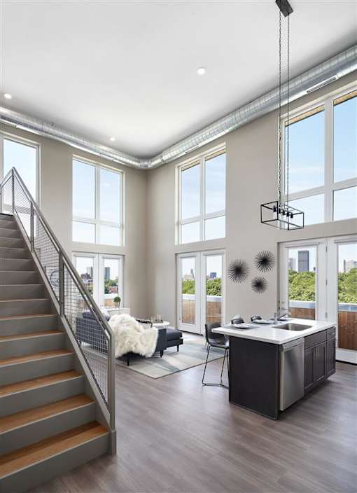 a large living room with a desk and a staircase