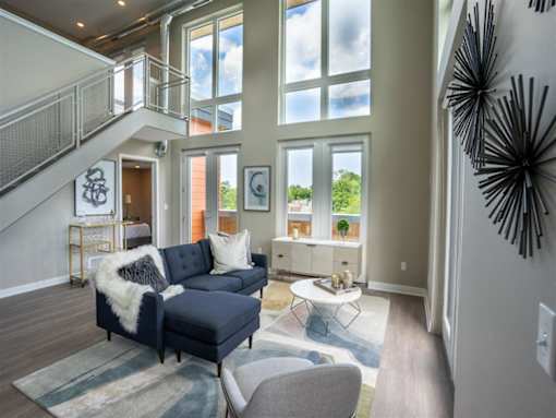 View of great room living area with floor to ceiling windows & stairway to second floor loft in background