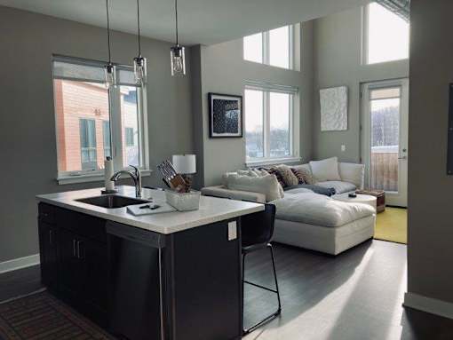 View from kitchen area of great room with floor to ceiling windows and wrap-around terrace in 2-story loft corner apartment