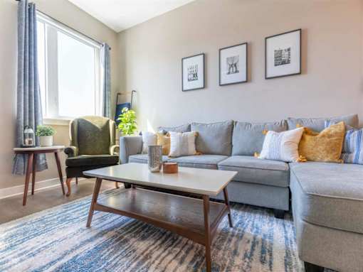 Spacious living room area in great room with L-shaped couch and large, bright windows