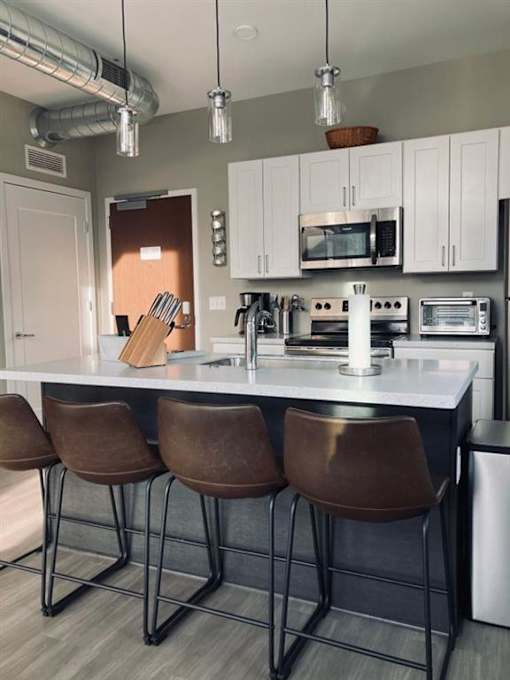 Well equipped kitchen with breakfast bar and stainless steel appliances including dishwasher, icemaker, microwave, refrigerator & electric stove