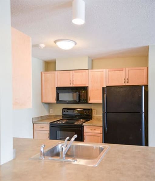 View of well equipped kitchen with black appliances, wood cabinetry, and breakfast bar View of well equipped kitchen with black appliances, wood cabinetry, and breakfast bar