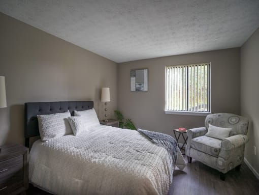 a bedroom with a bed and a chair and a window