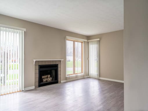 View of great room from dining area showing fireplace, faux-wood flooring, and slider to patio