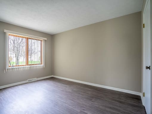 View of typical primary bedroom with large windows and faux plank flooring