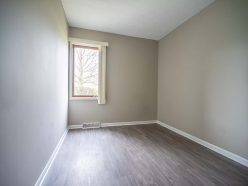 View of typical second bedroom with window and faux plank flooring
