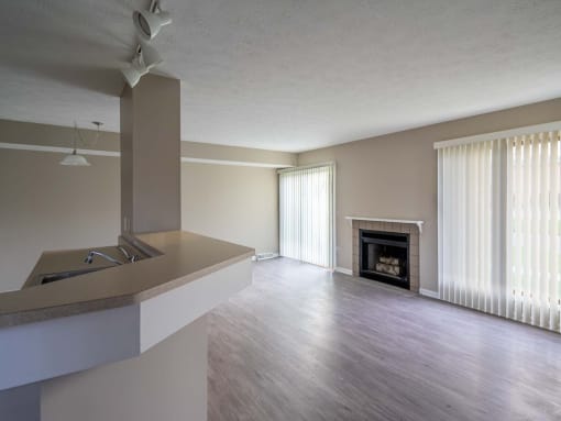 View from kitchen area breakfast bar of great room showing living and dining area as well as fireplace and faux plank flooring