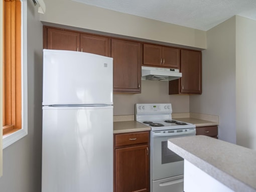 View of kitchen showing electric stove, refrigerator, and wood cabinetry