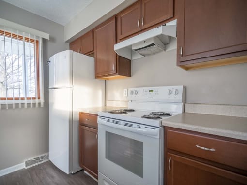 View of kitchen showing electric stove, refrigerator, and wood cabinetry