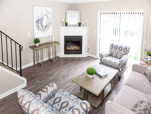 Open layout living/dining area with fireplace, sliding doors to private patio, & staircase to second floor (fireplaces in select apartment homes only)