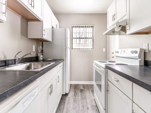 Modern kitchen with electric stove, dishwasher, refrigerator, faux granite countertops, and white cabinetry