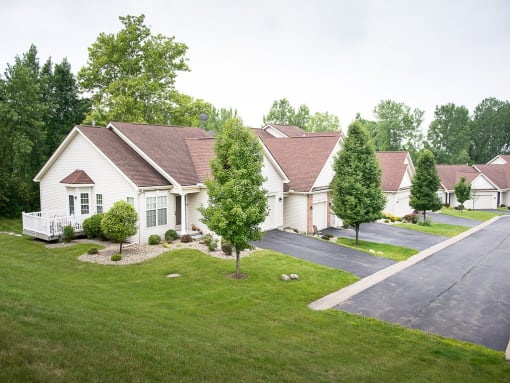 a neighborhood of white houses on a street with green grass and trees